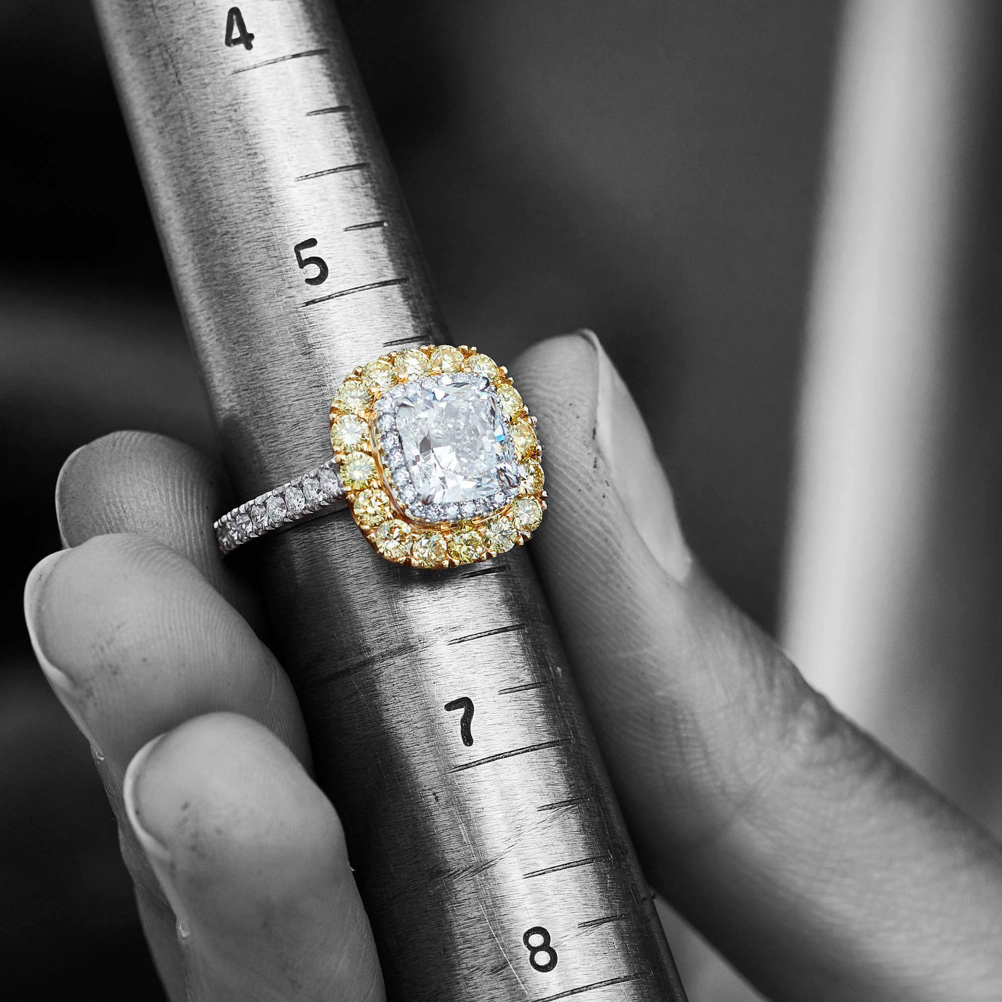 a white and yellow Garrard engagement ring resting on a finger sizer square
