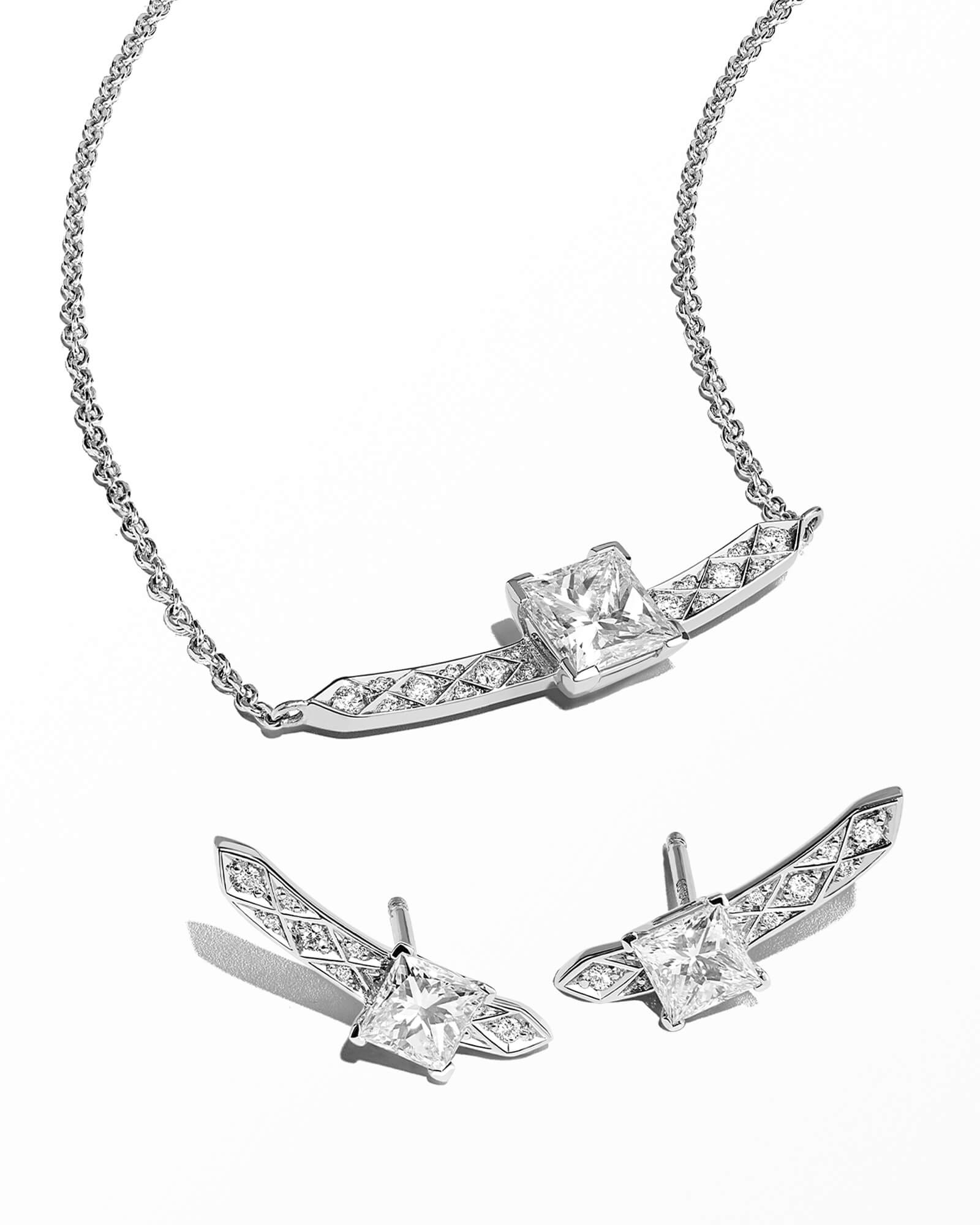 Close up of Garrard diamond bridal wedding day jewellery including a diamond pendant and earrings light grey background